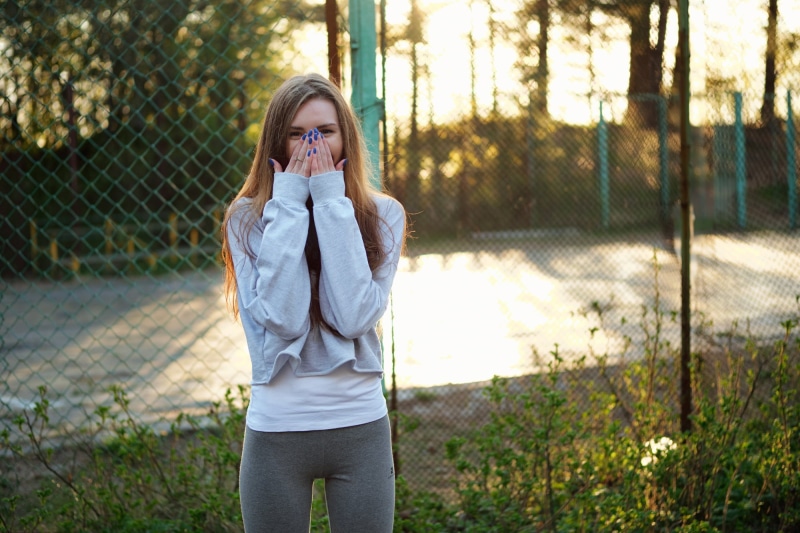 sports, hand on face, teenager, blue nails, front view, 1080P, three quarter length, outdoors, fence, straight hair, young adult, casual clothing, leggings