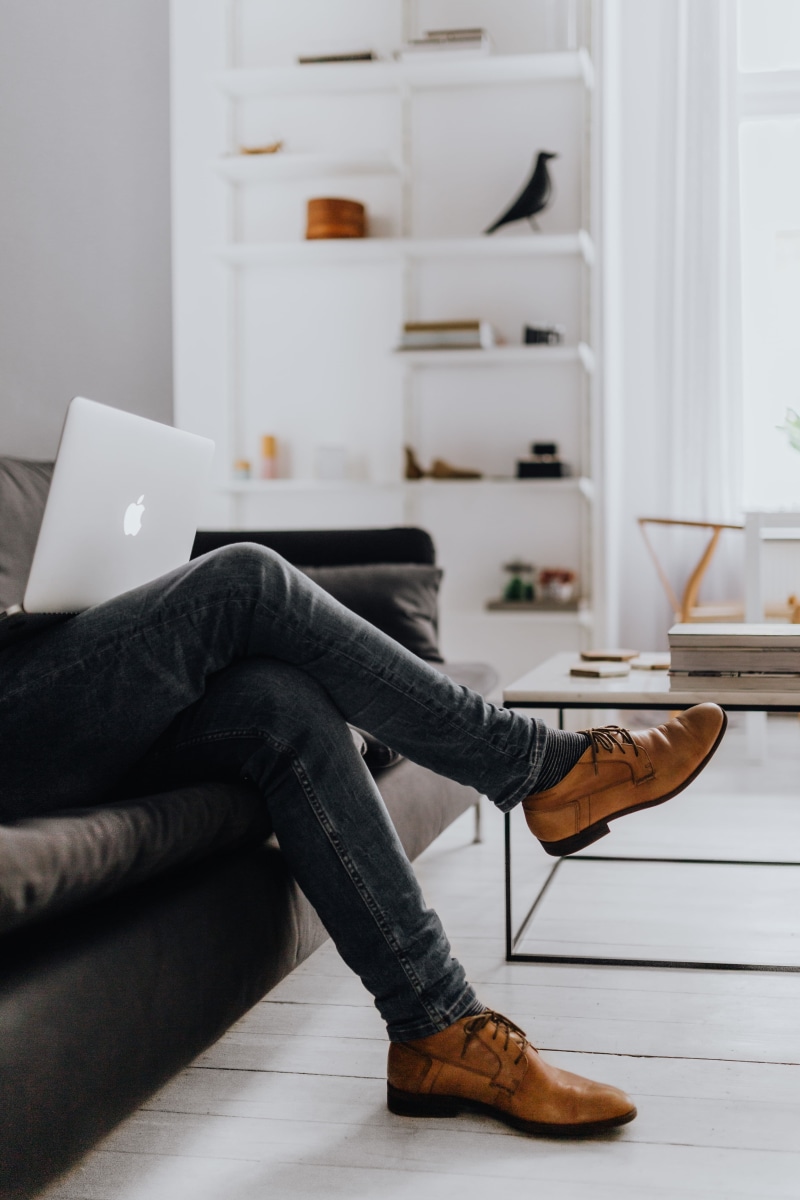 male, couch, sofa, man, black sofa, apartment, human body part, working, casual clothing, real people, leather shoes, full length, home interior, sitting