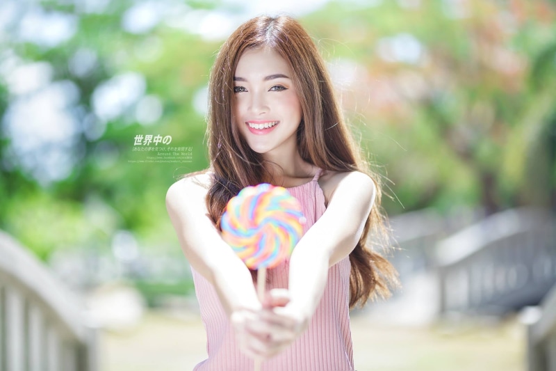Cup-E, outdoors, holding, hair, waist up, looking at camera, smiling, happiness, one person, young women, portrait, focus on foreground, Thai, young adult