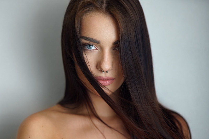 human face, hair in face, bare shoulders, beautiful woman, indoors, women, studio shot, gray, simple background, long hair, hairstyle, fashion, brunette