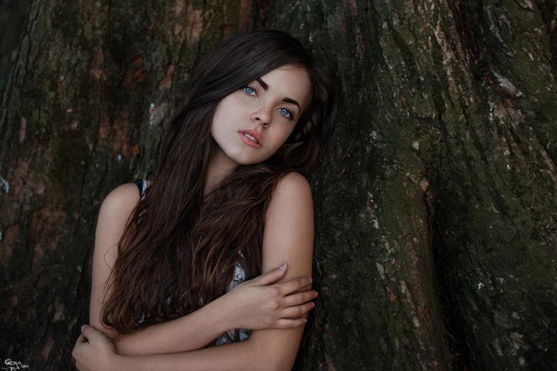 blue eyes, hairstyle, tree trunk, looking at camera, one person, sleeveless, portrait, beautiful woman, contemplation, woodland, forest, tree, women, brunette