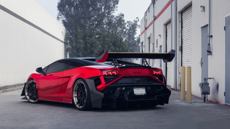 wheel, day, stationary, race car, mode of transportation, city, sign, tree, no people, lamborghini gallardo, street, garage, motor vehicle, supercar, built structure