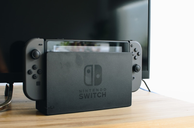 communication, black, switch, phone, beside, mobile phone, indoors, focus on foreground, screen, bumper, transportation, western script, nintendo, tv, camera