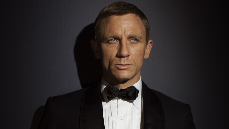 looking at camera, serious, headshot, black background, tuxedo, formalwear, well-dressed, males, one person, actor, mature adult, mature men, Daniel Craig