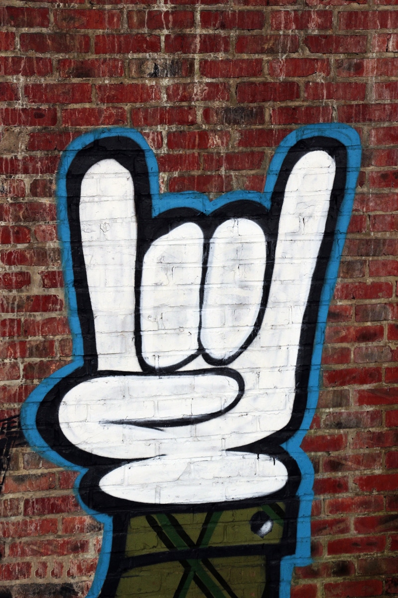 horned hand, creativity, mural, hand, text, pattern, devil horns, outdoors, hook em horns, heavy metal, brick wall, wall, brick, superstition, american football
