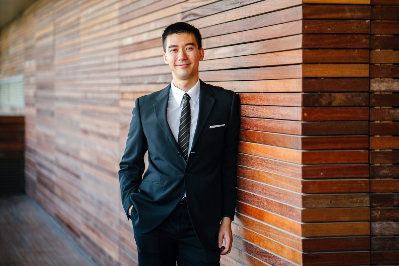 formal, suit, fine-looking, formal businesswear, friendly, one person, formalwear, day, facial expression, pants, professional, well-dressed, brick wall