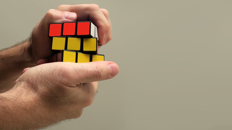 built structure, one person, close-up, people, childhood, puzzle, toy block, toy, multi colored, solution, human limb, leisure, rubiks, hold, cube, colored background