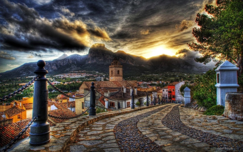 building, religion, near, mountains, place of worship, sunset, flowers, the past, tower, sky, hill, medieval, blue, dusk, city, village, green, spirituality
