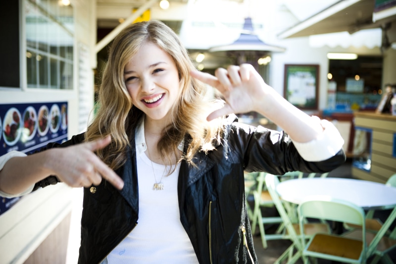 Chloë Grace Moretz, blond hair, grace, indoors, toothy smile, happiness, real people, teeth, lifestyles, front view, standing, smiling, one person, hairstyle