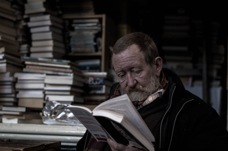 home, one person, stack, shelf, old man, mature adult, men, man, looking, books, reading, dog, publication, mature men, large group of objects, architecture