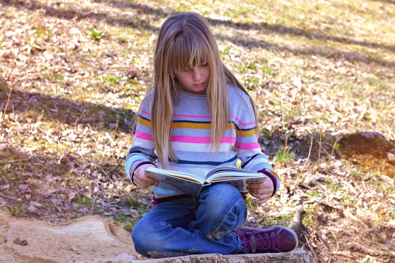 education, outdoors, day, field, lifestyles, child, females, people, jeans, hairstyle, learning, grass, one Person, innocence, daytime, real people, book