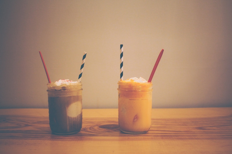 dairy product, household equipment, food, drinking straw, indulgence, objects, straws, smoothies, indoors, drinking glass, still life, tbale, clear, wooden