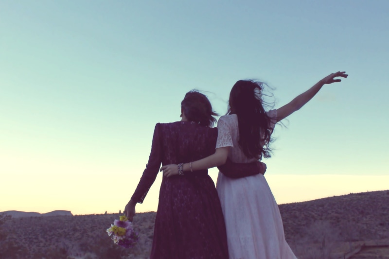 hugging, leisure activity, bonding, two people, fashion, positive emotion, land, desert landscape, daytime, love, vintage fashion, human arm, nature, emotion