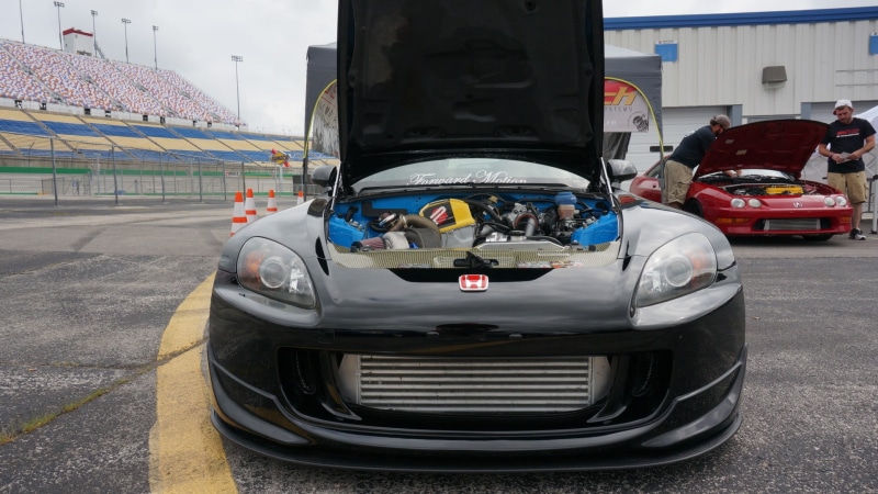 outdoors, road, day, racecar, wheel, incidental people, black, mode of transportation, competition, real people, motor racing track, race tracks, building exterior
