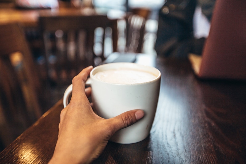 refreshment, Cafe, table, indoors, drinks, food/Drink, drink, held, glass, drinking, cup, relaxation, finger, one Person, restaurant, adult, latte, human hand