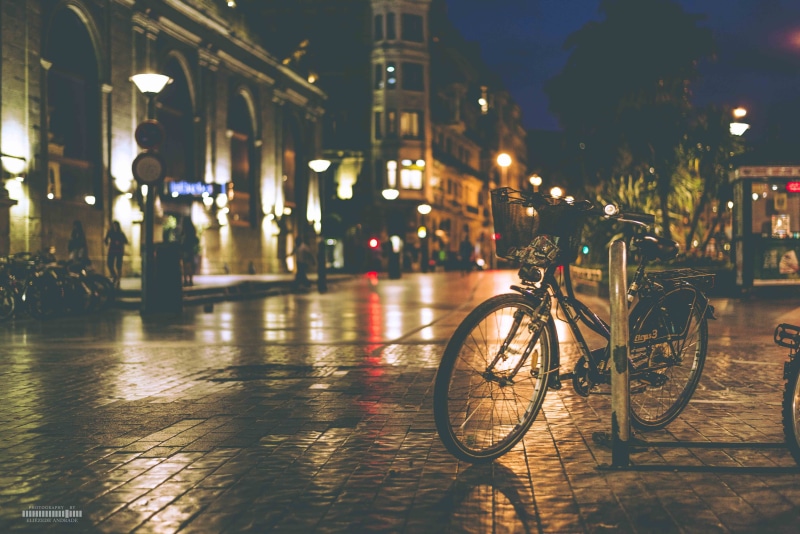 outdoors, building exterior, stationary, street, concrete, night, city, street light, built structure, city life, bicycle, architecture, black, building