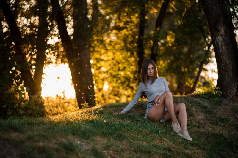 tree trunk, hair, jean shorts, trees, one person, grass, relaxation, women, plant, adult, casual clothing, land, brunette, hairstyle, beautiful woman, sunlight