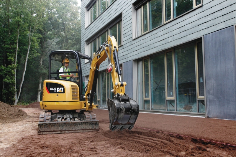 man, earthmoving, outdoors, building exterior, built structure, yellow, caterpillar, street, cat, earth mover, nature, mode of transportation, land vehicle