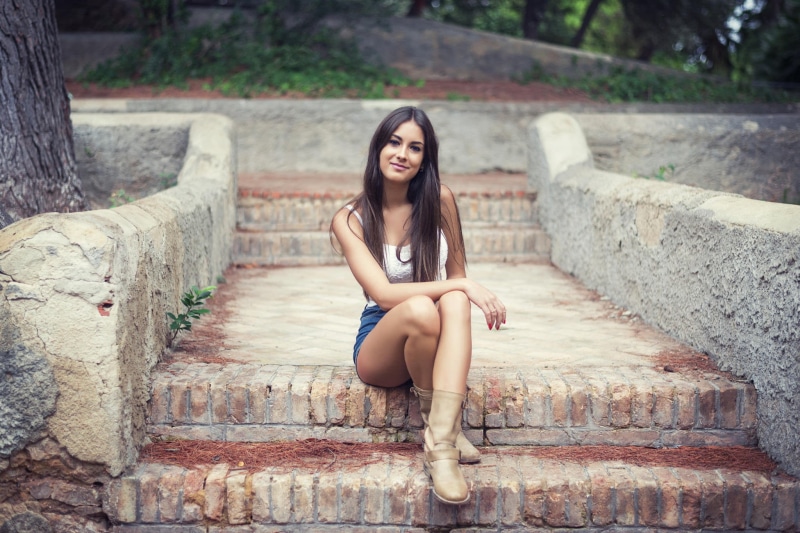 outdoors, beautiful woman, sitting, young women, architecture, front view, staircase, women, leisure activity, lifestyles, fashion, long hair, jean shorts