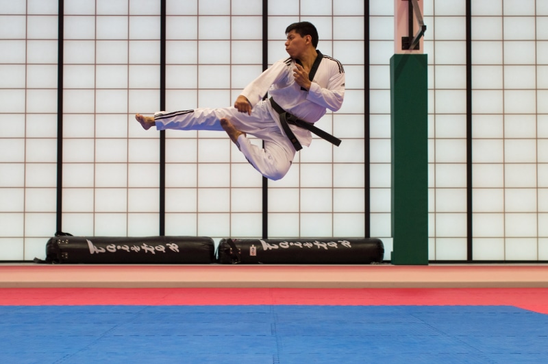 emotion, air, one person, smiling, judo, sport, player, clothing, indoors, male, 5K, strike, kick, mid-air, adult, full length, jumping, taekwondo, man