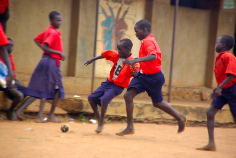 medium group of people, people, competition, boys, group of people, wall, goal, player, ball, motion, shorts, feet, day, dust, child, school, uniform, professional