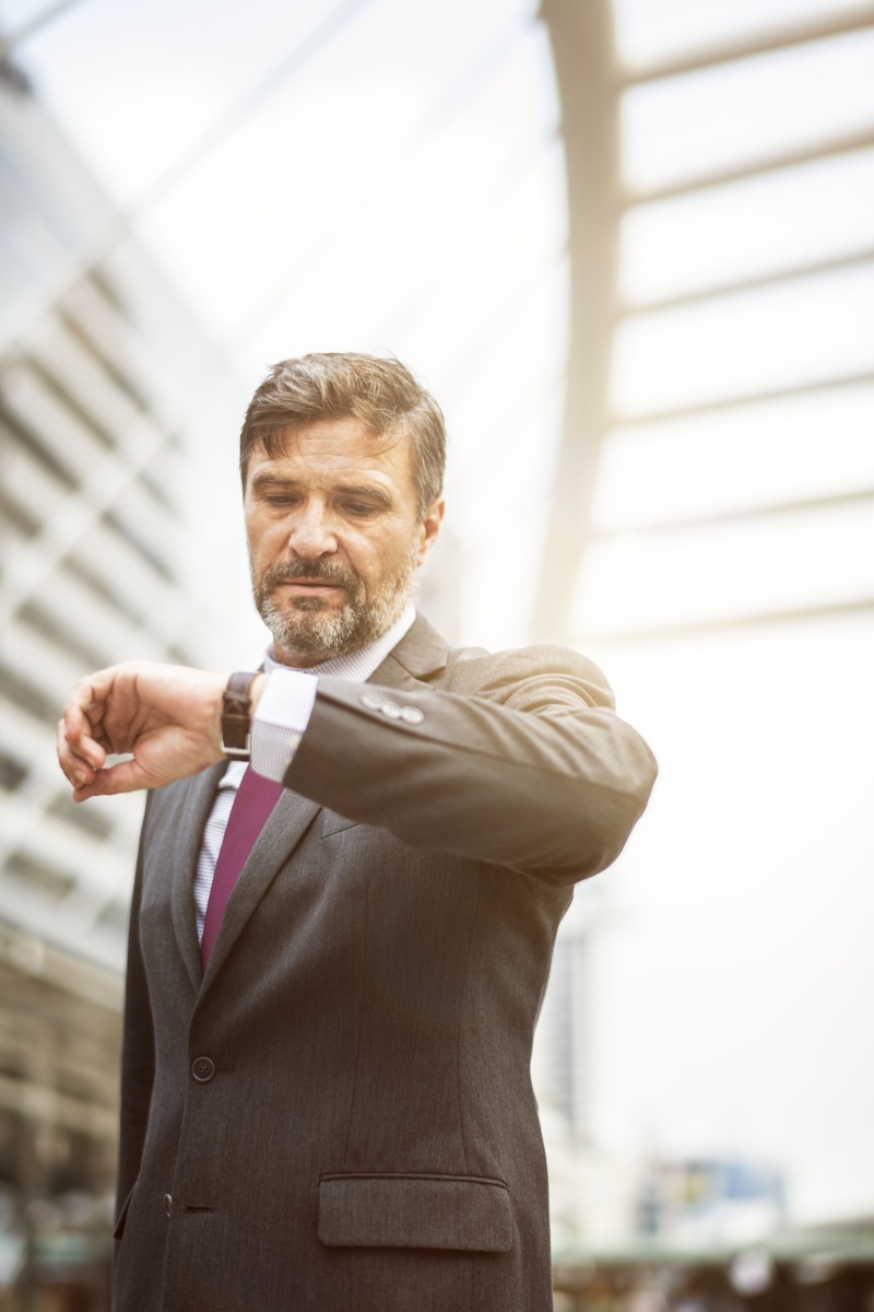 standing, focus on foreground, adult, corporate, busy, on time, business person, males, mature men, beard, checking the time, 5K, businessman, concerned