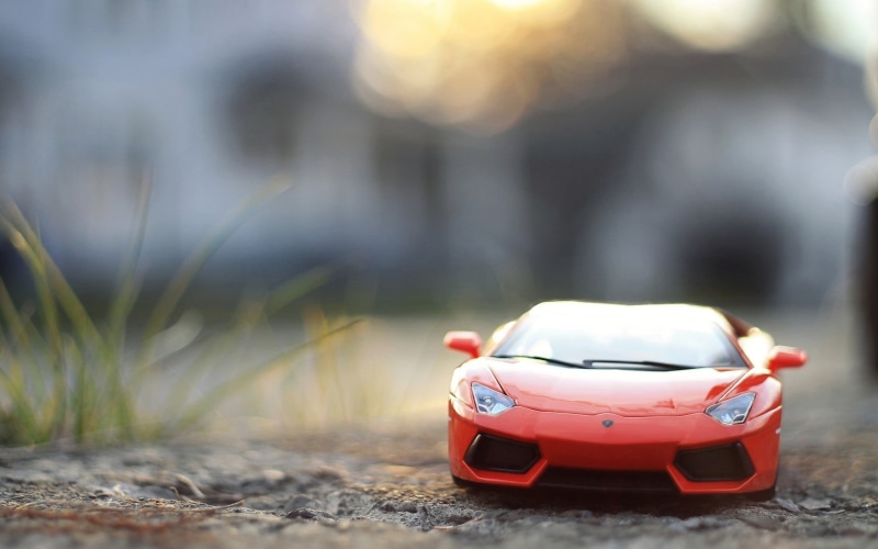 transportation, close-up, land vehicle, model, die, red, 1080P, toy, outdoors, macro, sunlight, selective focus, car, Lamborghini, grass, plant, mode of transportation