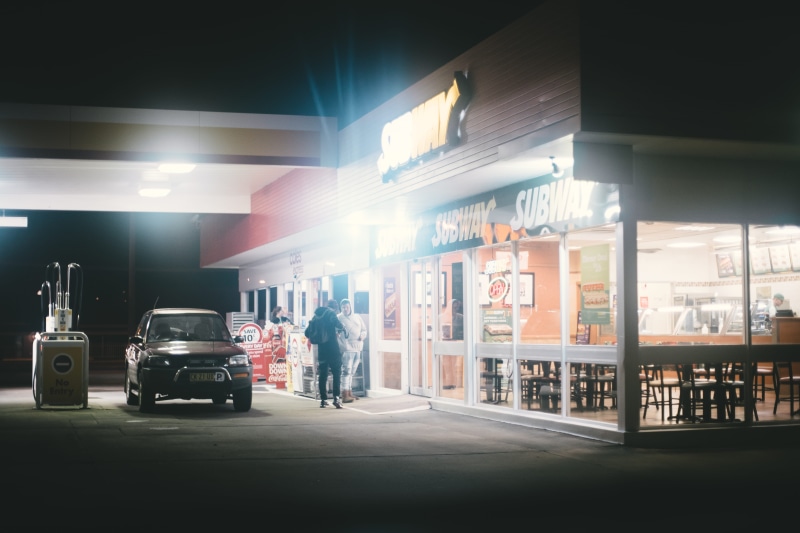 incidental people, sedan, full length, two, rear view, built structure, gas station, subway, black, street, one person, city, light, building, person, urban