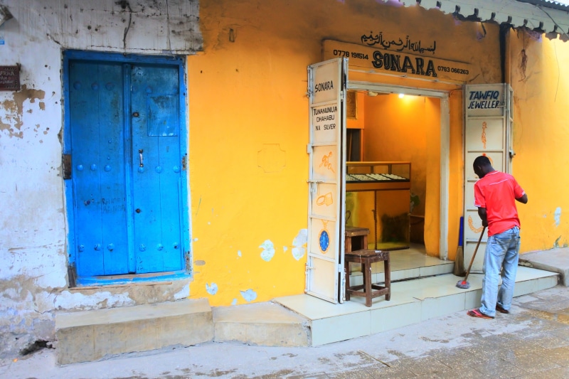 zanzibar, built structure, text, wall - building feature, outdoors, entrance, door, one person, men, casual clothing, africa, standing, full length, doorway