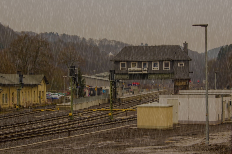 high angle view, day, transportation, express train, outdoors, mode of transportation, raining, railway, platform, residential district, sky, gleise, track