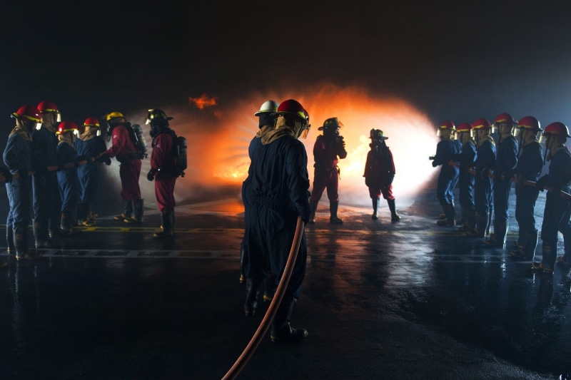service, equipment, men, practice, leisure activity, firemen, water hose, standing, real people, holding, group of people, adult, training, safety, smoke - physical structure