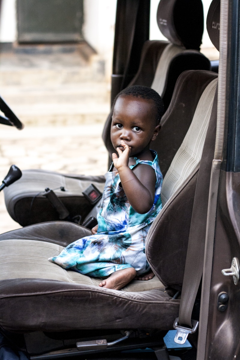 real people, gloria, sitting, one person, portrait, 4K, day, jeep, cute, childhood, casual clothing, dress, child, daughter, three quarter length, uganda
