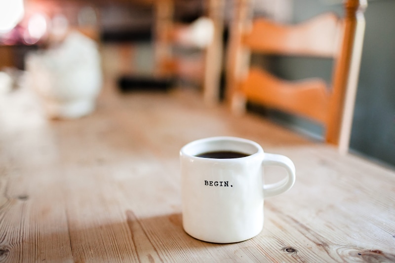 western script, begin, coffee mug, beverage, morning, communication, refreshment, coffee, cup, coffee shop, hot drink, brown, coffee - drink, table, wood - material