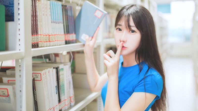 education, indoors, holding, intelligence, book, studying, shelf, hairstyle, Asian, looking at viewer, student, bookshelf, casual clothing, library, portrait