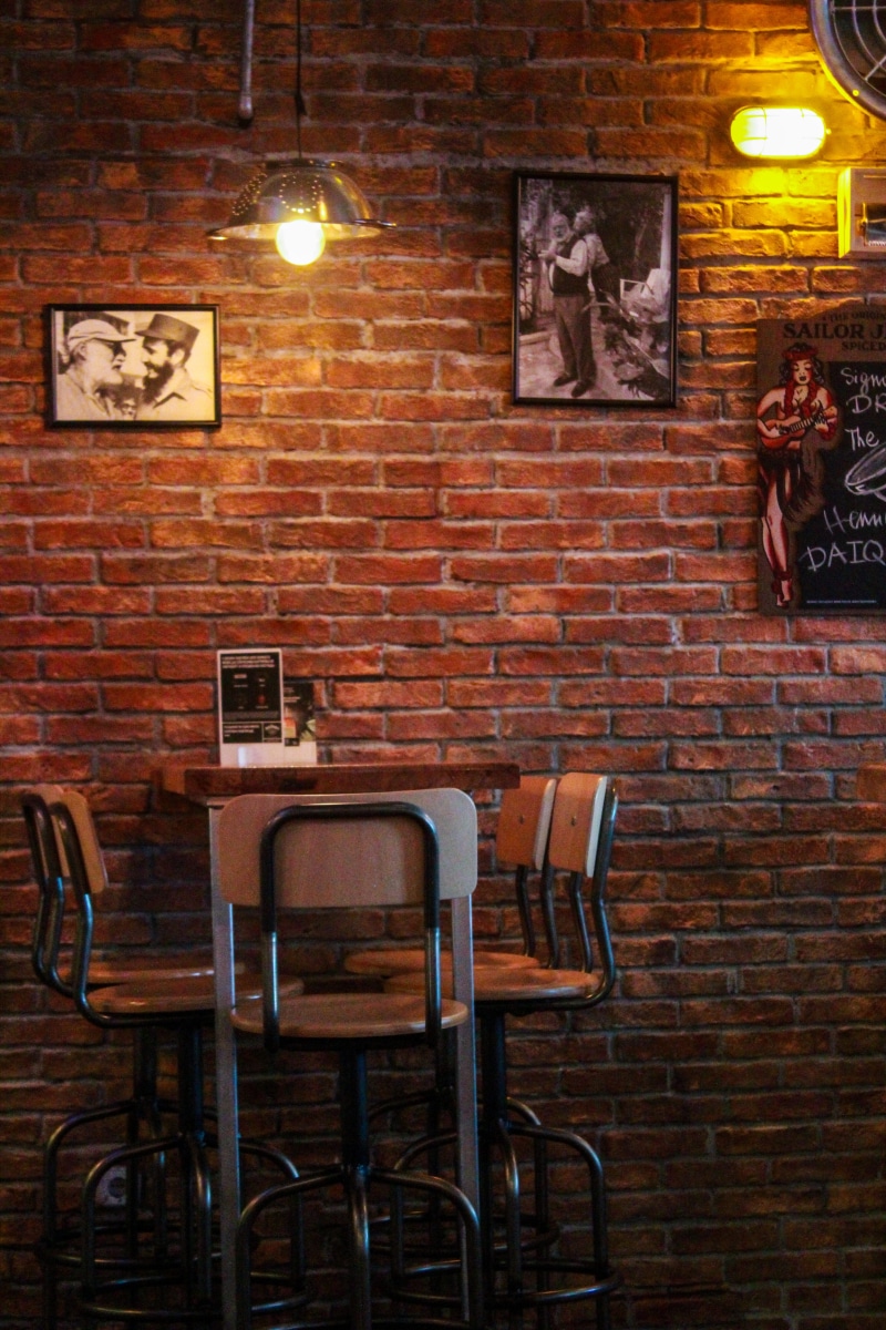 random, wall - building feature, brick, indoors, absence, bar - drink establishment, western script, text, chair, 5K, illuminated, table, brick wall, seat