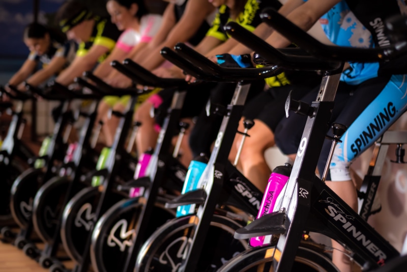 cycle, bicycle, person, multi colored, human body part, wheel, spinning, arts culture and entertainment, equipment, class, night, adult, gym, transportation