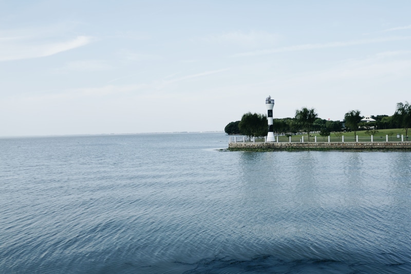 water, blue, day, outdoors, beauty in nature, time, house, white, on the edge, light, horizon, point, coast, island, body, building, tranquil scene, sea