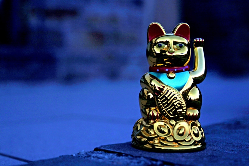 close-up, animal representation, waving cat, 4K, table, focus on foreground, maneki neko, single object, figurine, indoors, religion, deco, thailand, still life