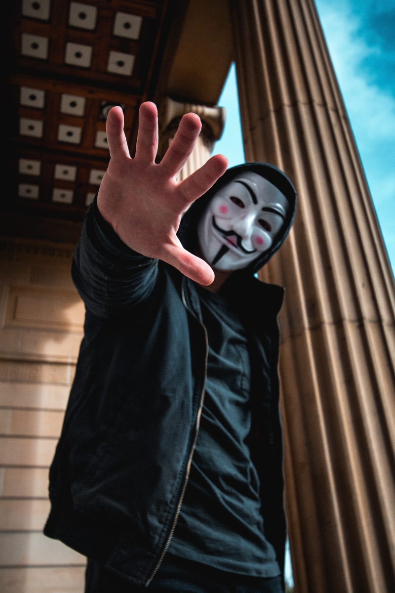 casual clothing, wearing, young women, building, activist, mask, looking at camera, person, hand sign, man, fashion, guy, one person, three quarter length