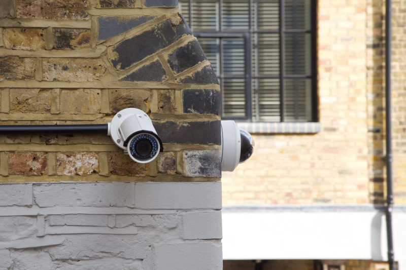 watch, brick wall, alarm, day, brick, wood - material, metal, observe, building, focus on foreground, record, security, watching, guard, outdoors, building exterior