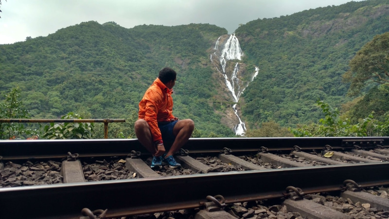 rock - object, looking at view, waterfall, 4K, nature, outdoors, indian summer, solid, real people, sitting, day, indian, waterfalls, men, goa, railroad track