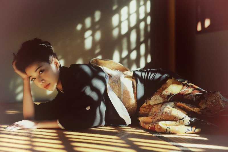sitting, sunlight, relaxation, one person, looking at camera, day, 2K, hairstyle, leisure activity, table, Asian, geisha, on the floor, lifestyles, waist up