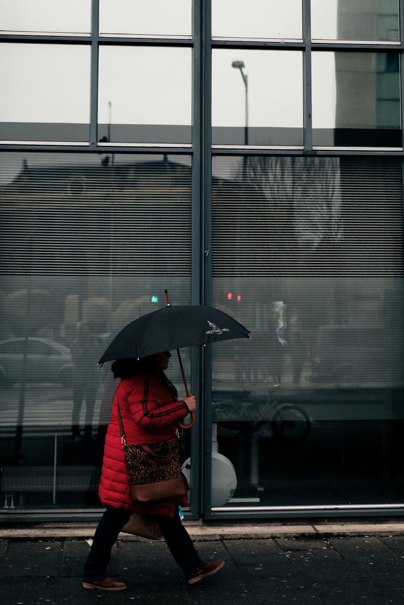 accessories, umbrella, city, outdoors, person, transportation, machine, human, spoke, rain, overcoat, building exterior, rainy season, one person, monsoon