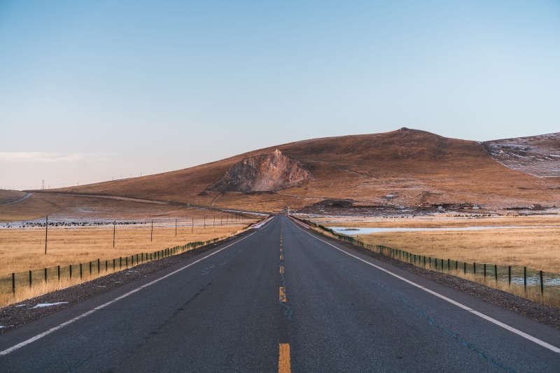 dividing line, straight, overpass, outdoors, remote, day, gravel, mountain, empty road, the way forward, plateau, sky, city, arid climate, no people, mesa