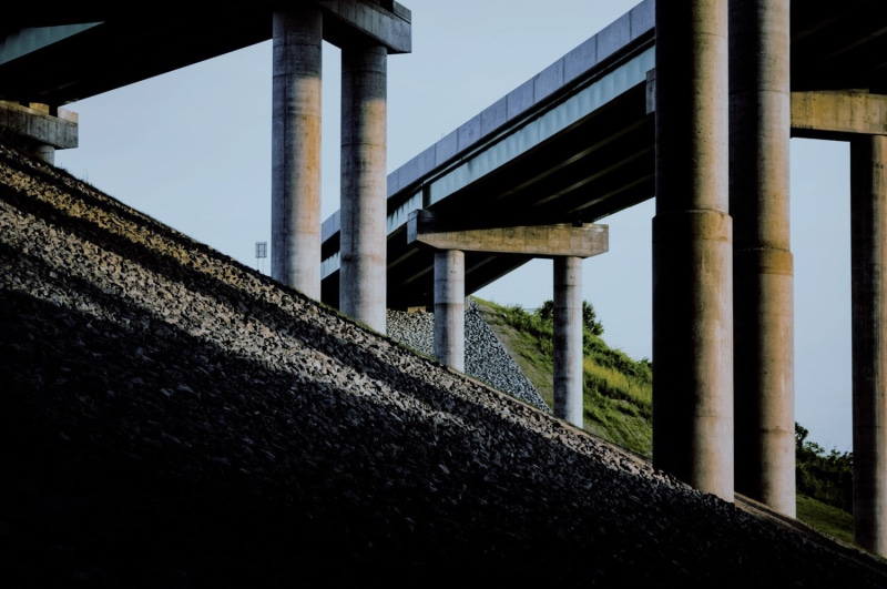 clear sky, building exterior, sunlight, plant, day, outdoors, bridge, transportation, overpass, architecture, nature, no people, sky, low angle view, railing