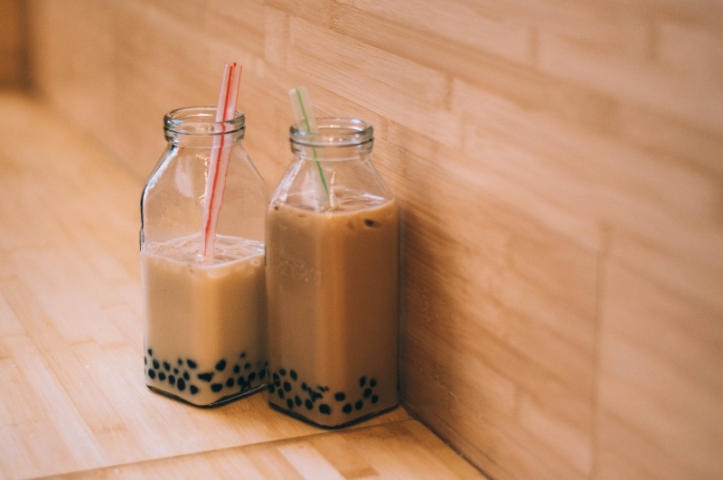 fudge, milk tea, dairy product, wood - material, food, domestic room, chocolate, milk, smoothie, bottle, boba, asian, dessert, table, straws, cafe, beverage
