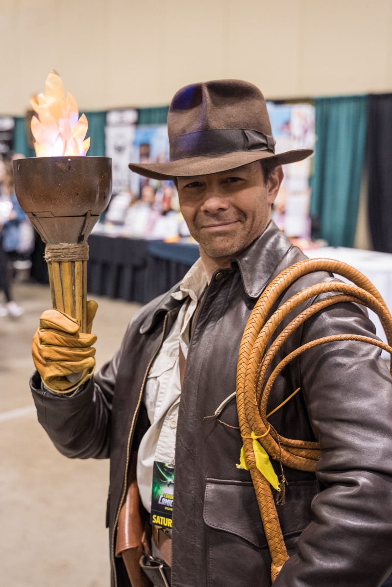 electronics, day, apparel, waist up, man, confidence, standing, screen, brown, hat, focus on foreground, whip, looking at camera, person, happiness, emotion