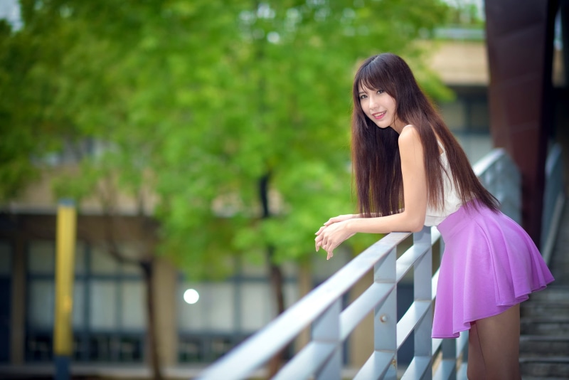 looking at viewer, teenager, trees, fashion, long hair, beauty, young adult, looking at camera, adult, outdoors, smiling, lifestyles, brunette, hair, leisure activity