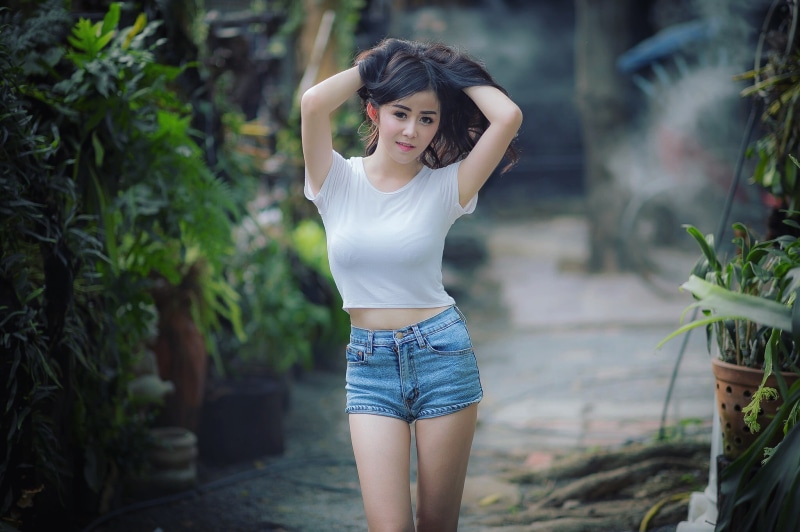 plant, focus on foreground, shorts, front view, wearing, hair, three quarter length, blue, real people, brunette, hand in hair, adult, young women, photo
