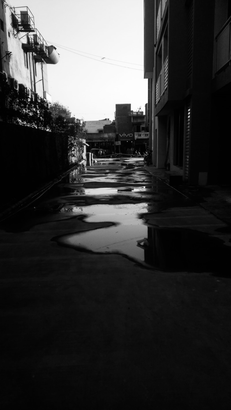 concrete, building exterior, no people, canopy, surface level, transportation, urban, corridor, puddle, road, street, path, sidewalk, sky, building, day